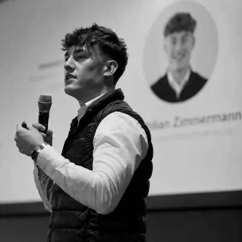 Maximilian Zimmermann spricht mit Mikrofon auf einer Bühne
